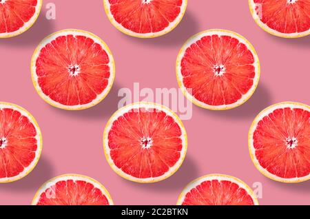Modello di frutta. Coloratissime fette fresche di pompelmo su sfondo rosa pastello. Dalla vista dall'alto. Profondità di campo completa. Foto Stock