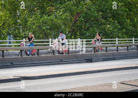 LONDRA, INGHILTERRA - 27 MAGGIO 2020: Vista di un gruppo di ciclisti sorridenti che cavalcano sul ponte Waterlook al sole durante la pandemia COVID-19 Foto Stock