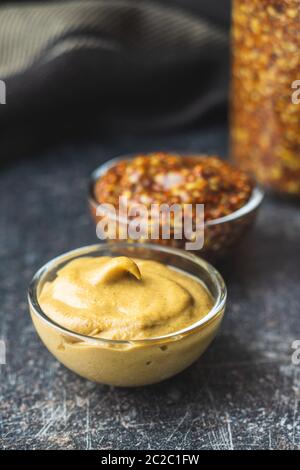 Giallo senape e grano intero senape nella ciotola sul vecchio tavolo da cucina. Foto Stock