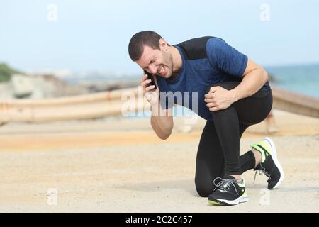 Runner dolorosa sofferenza dolore al ginocchio per chiedere aiuto chiamando al telefono Foto Stock