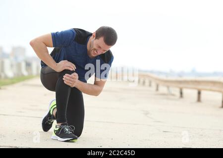 Pareggiatore dolorosa lamenta sofferenza dolore al ginocchio dopo lo sport su un modo concreto Foto Stock