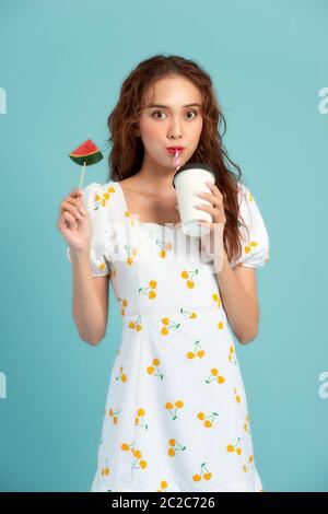 Ritratto di moda bella ragazza fredda beve un succo da tazza tiene fetta di anguria Foto Stock