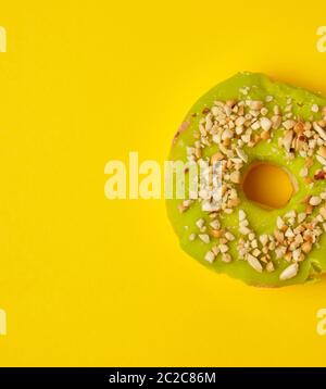 Dolce rotondo verde pistacchio ciambella cosparso con dado di massa su uno sfondo giallo, vista dall'alto Foto Stock