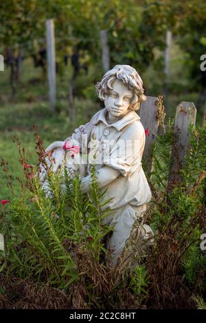 Saint Emilion, Francia - 12 settembre 2018:la statua di un ragazzo tenendo un cesto con uva sullo sfondo dei vigneti in Saint Emilion regione. Fr Foto Stock