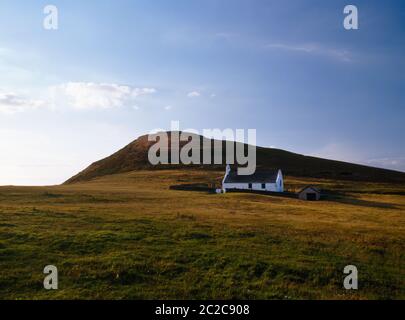 Vista a nord-ovest della chiesa di Santa Croce riparata dal promontorio di Foel y Mwnt, Cardigan; Galles; Regno Unito. C 13-14 cappella pellegrina sul sito della cella di un santo celtico. Foto Stock