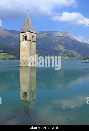 La torre della chiesa di Graun con la riflessione nel Reschensee Foto Stock