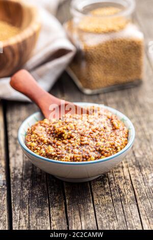 Grano intero senape nella ciotola sul vecchio tavolo in legno. Foto Stock