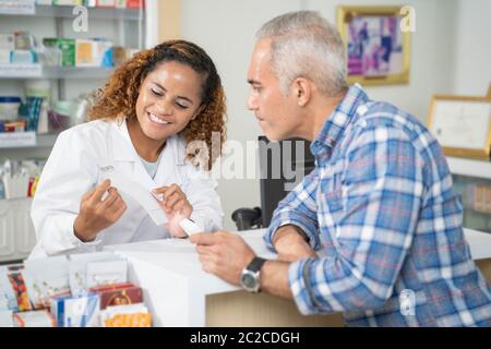 Le farmacie femminili stanno tenendo le prescrizioni dai clienti nelle farmacie. Foto Stock