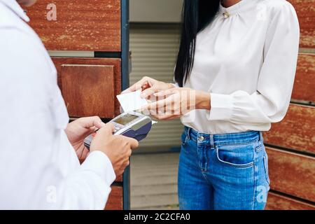 Colpo di primo piano orizzontale medio di donna irriconoscibile che paga per il servizio di consegna del cibo con carta di credito Foto Stock