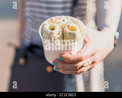 Tenere a mano il gelato arrotolato in una tazza conica Foto Stock