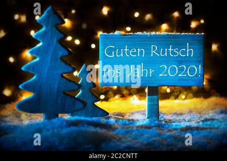 Segno con testo tedesco Guten Rutsch 2020 significa felice anno nuovo 2019. Blue albero di Natale con la neve e la magia luci incandescenti In Backround. Carta per Seaso Foto Stock