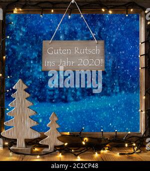 Segno con testo tedesco Guten Rutsch Ins Jahr 2020 significa felice anno nuovo 2018. Sul telaio di una finestra con paesaggio invernale con la neve. Vista di alberi innevati al di fuori Foto Stock