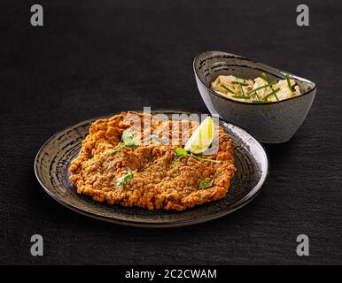 Carne di vitello gigante schnitzel viennesi servito con insalata di patate con erba cipollina Foto Stock