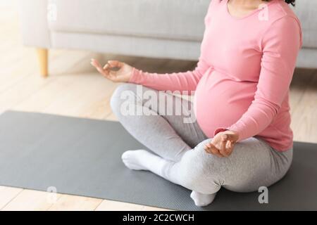 Donna incinta nera irriconoscibile in posa di loto Foto Stock