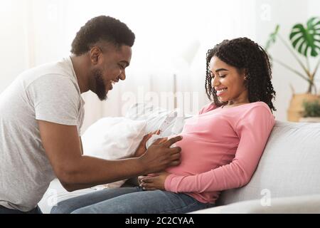 Aspettandosi moglie e marito che mettono le cuffie sul ventre Foto Stock