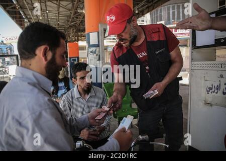 17 giugno 2020, Siria, Idlid Città: Un uomo paga il gas in lire turche invece delle lire siriane (lire siriane) in un distributore di benzina nella città di Ilib, detenuta dai ribelli, dopo che le autorità monetarie locali hanno deciso di iniettare il mercato con la valuta turca e con i dollari americani invece della valuta nazionale siriana, che è crollata nelle ultime settimane. Mercoledì la banca centrale siriana ha aumentato il tasso di cambio del dollaro contro la sterlina locale, mentre il nuovo cosiddetto 'Caesar Act' statunitense è entrato in vigore mercoledì. L’atto penalizza individui, istituzioni e aziende, sia siriane che straniere, suppo Foto Stock