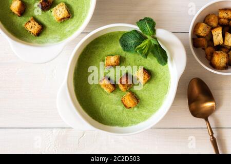 Deliziosa zuppa di crema di piselli giovani e menta con crostini di pane bianco, cibo sano Foto Stock