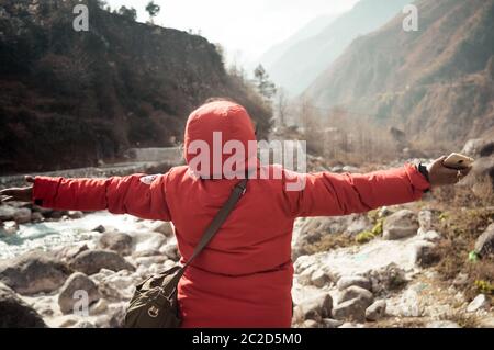 Sul bordo di un himalayan scogliera rocciosa una donna nomade teso le mani verso il cielo come un segno di libertà o la vittoria. Una fantastica valle himalayana di fro Foto Stock