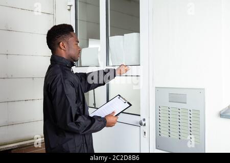 Uomo in piedi davanti alla porta di casa bussa alla porta Foto Stock