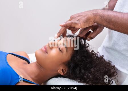 Close-up del terapeuta di mano di eseguire Trattamento Reiki sul giovane donna In Spa Foto Stock