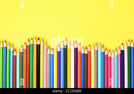 Colorate matite colorate visualizzate in onda su sfondo giallo. Foto Stock