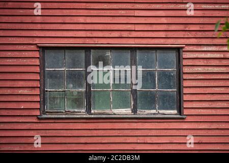Vecchie finestre rustiche e sporche in un vecchio edificio di legno dipinto di rosso. Immagine ravvicinata dall'esterno. Foto Stock