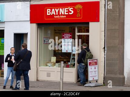 Dundee, Tayside, Scozia, Regno Unito. 17 Giugno 2020. Regno Unito Meteo: Clima umido e soleggiato in tutto il Nord-Est della Scozia. I residenti locali fanno shopping essenziale durante la fase 2 di Covid-19, a condizione che rispettino le linee guida del Coronavirus dei governi di distanza sociale e indossare maschere facciali protettive. La gente che si acciglia fuori della panetteria della famiglia Bayne`s a Lochee High Street a Dundee. Credit: Dune Photographics/Alamy Live News Foto Stock