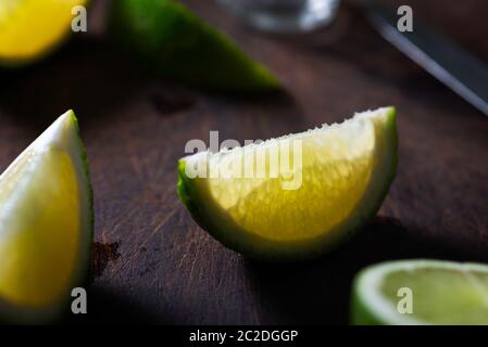 limes e Cachaça su un tavolo di legno, cucina brasiliana Foto Stock