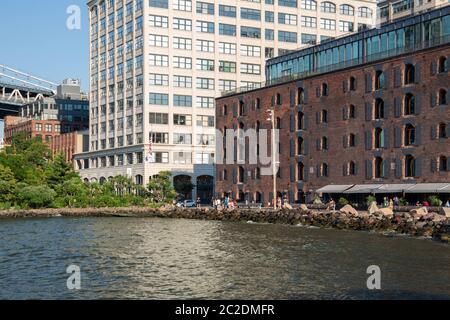 New York, Città / STATI UNITI D'America - 10 LUG 2018: edifici di lusso e negozi in Dumbo Ponte di Brooklyn Park Foto Stock