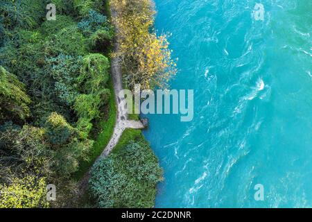 Top-down drone vista di rapide del fiume di montagna con un piccolo molo di pietra a bordo del legno. Close up. Foto Stock