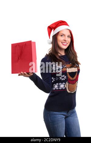 Un ritratto di una bella sorridente ragazza in inverno i vestiti che indossa Santa's hat, tenendo un carrello di un sacchetto, isolato su sfondo bianco. Foto Stock