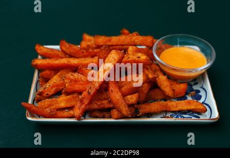 Porzione di deep dolce fritto patatine o patate fritte con salsa di immersione sulla piastra sopra il tavolo, ad alto angolo di visione Foto Stock