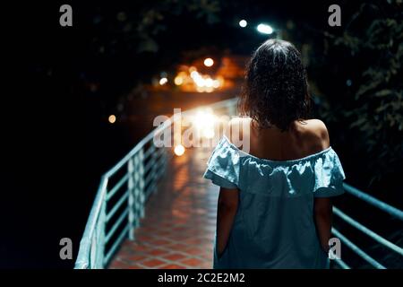 Giovane donna sola che cammina sul ponte di notte Foto Stock