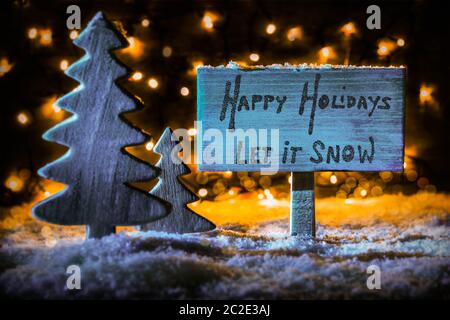 Cartello in legno con la calligrafia Inglese Buone Vacanze Let It Snow Christmas Tree sulla neve e le luci fairy in background. Spotlight blu Foto Stock