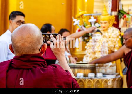 Un monaco buddista scattare una foto alla Pagoda Shwedagon, Yangon, Myanmar. Foto Stock