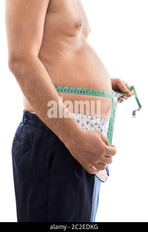 Close up di un giovane maschio con problemi di peso, misurando la sua grande stomaco con un nastro di misurazione, isolati su sfondo bianco. Foto Stock