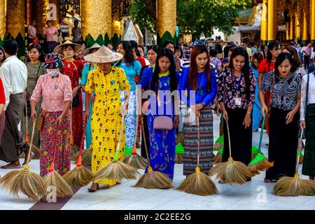 Le donne che visitano la Pagoda di Shwedagon prendono parte al rituale giornaliero di pulizia e spazzare i terreni, la Pagoda di Shwedagon, Yangon, Myanmar. Foto Stock