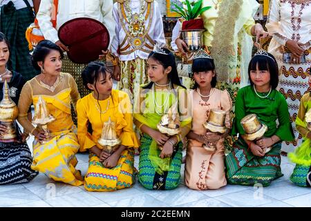 I bambini vestiti con colori prendono parte AD UNA cerimonia di noviziazione/Shinbyu alla pagoda di Shwedagon, Yangon, Myanmar. Foto Stock