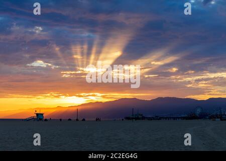 Splendido tramonto dietro le montagne di Santa Monica con il molo e la spiaggia di Santa Monica in prima linea. Foto Stock