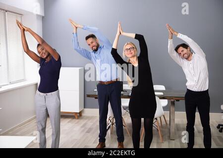 Ritratto di un sorridente Giovani Imprenditori fare yoga in ufficio Foto Stock