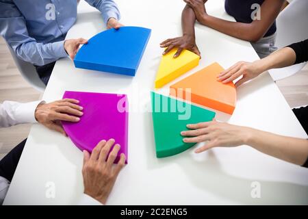 Elevato angolo di visione del business le mani il collegamento Multi pezzi colorati del grafico a torta Foto Stock