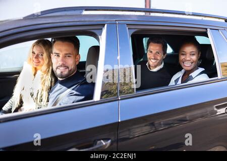 Gruppo di amici sorridente in auto sulla strada viaggio insieme guardando fuori dalla finestra Foto Stock