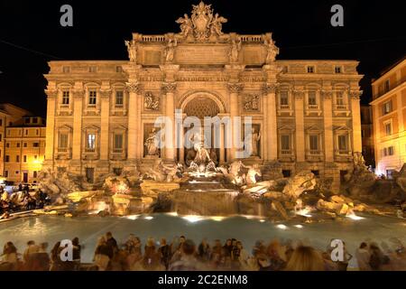 Scena notturna della famosa Fontana di Trevi a Roma, con folle di turisti che si godono questo capolavoro dell'architettura italiana. Foto Stock