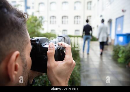 Giovane uomo Paparazzi fotografo scatta una foto con sospetto del giovane camminare insieme utilizzando una fotocamera Foto Stock