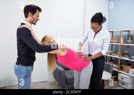 Un massaggio africano terapista massaggiatore Donna Incinta attesa da suo marito a casa Foto Stock