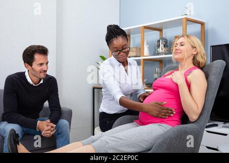 Tranquillo Donna Incinta avente un rilassante massaggio da africani terapista femmina a casa Foto Stock