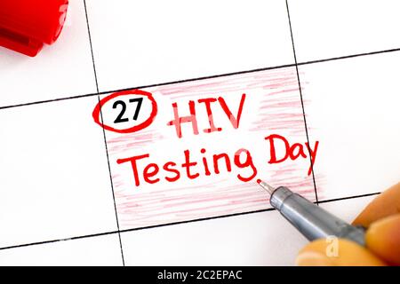 Dita donna con penna che scrive promemoria HIV Test Day in calendario. Giugno 27. Foto Stock