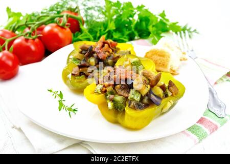 Peperoni ripieni con funghi, pomodori, zucchine, melanzane e cipolle, condito con vino, aglio, timo e spezie in piastra bianca su asciugamano aga Foto Stock