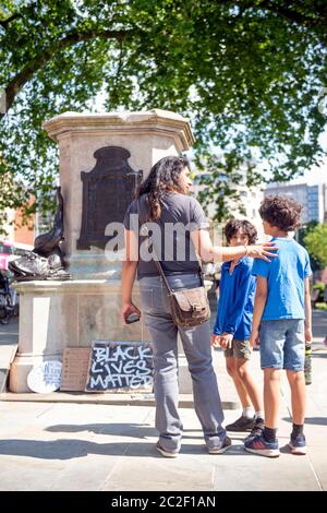 Una famiglia al basamento rotto nel luogo della statua rovesciata di Edward Colston a Bristol - 8 giugno 2020 Foto Stock