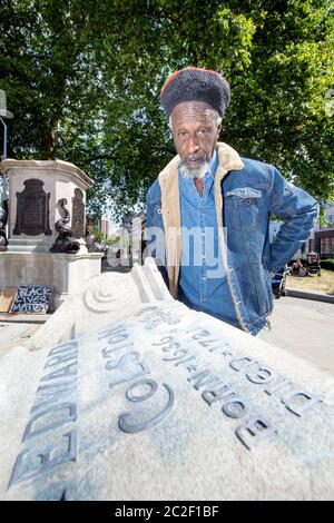 Lo scrittore e musicista Simbarashe Tongogara sormonda una sezione di zoccolo rotto nel sito della statua rovesciata di Edward Colston a Bristol - 8 giu Foto Stock